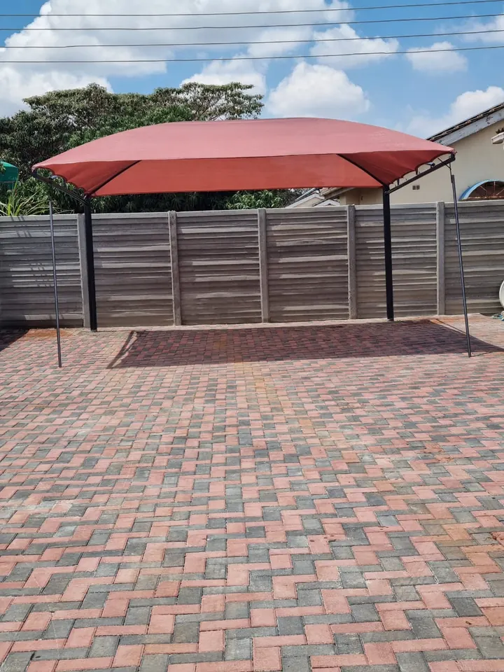 Red cantilever shade over a paved parking area